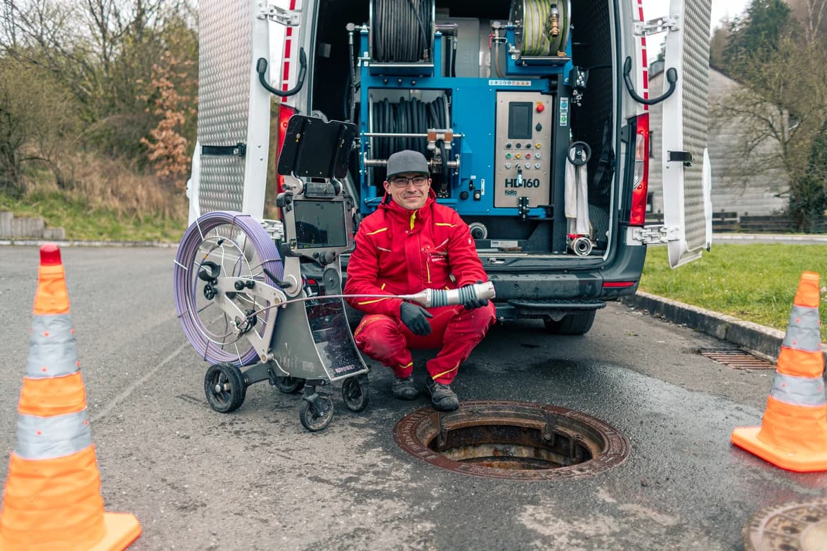 Techniker der Hermann Schäfer Rohrreinigungsservice e.K. mit Kanal-TV-Kamera und Einsatzfahrzeug am geöffneten Kanalschacht