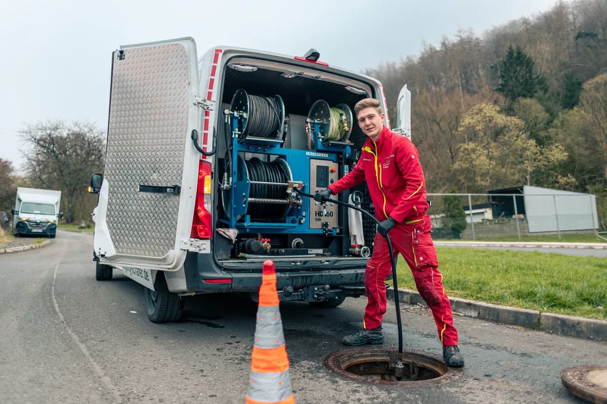Techniker bei der Rohrreinigung am offenen Kanalschacht in Biedenkopf