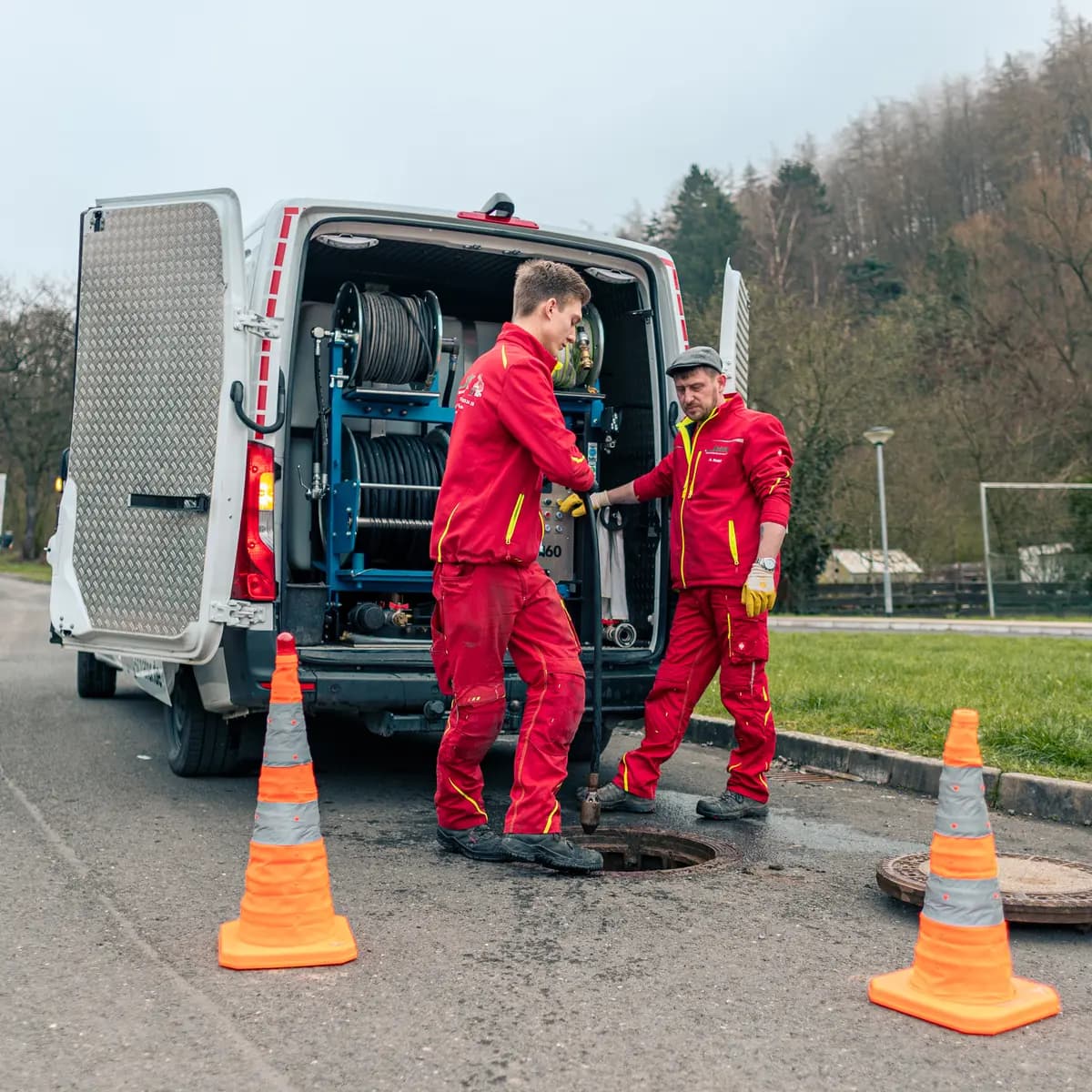 Techniker reinigt Kanal per Hochdruckspülung am Haus