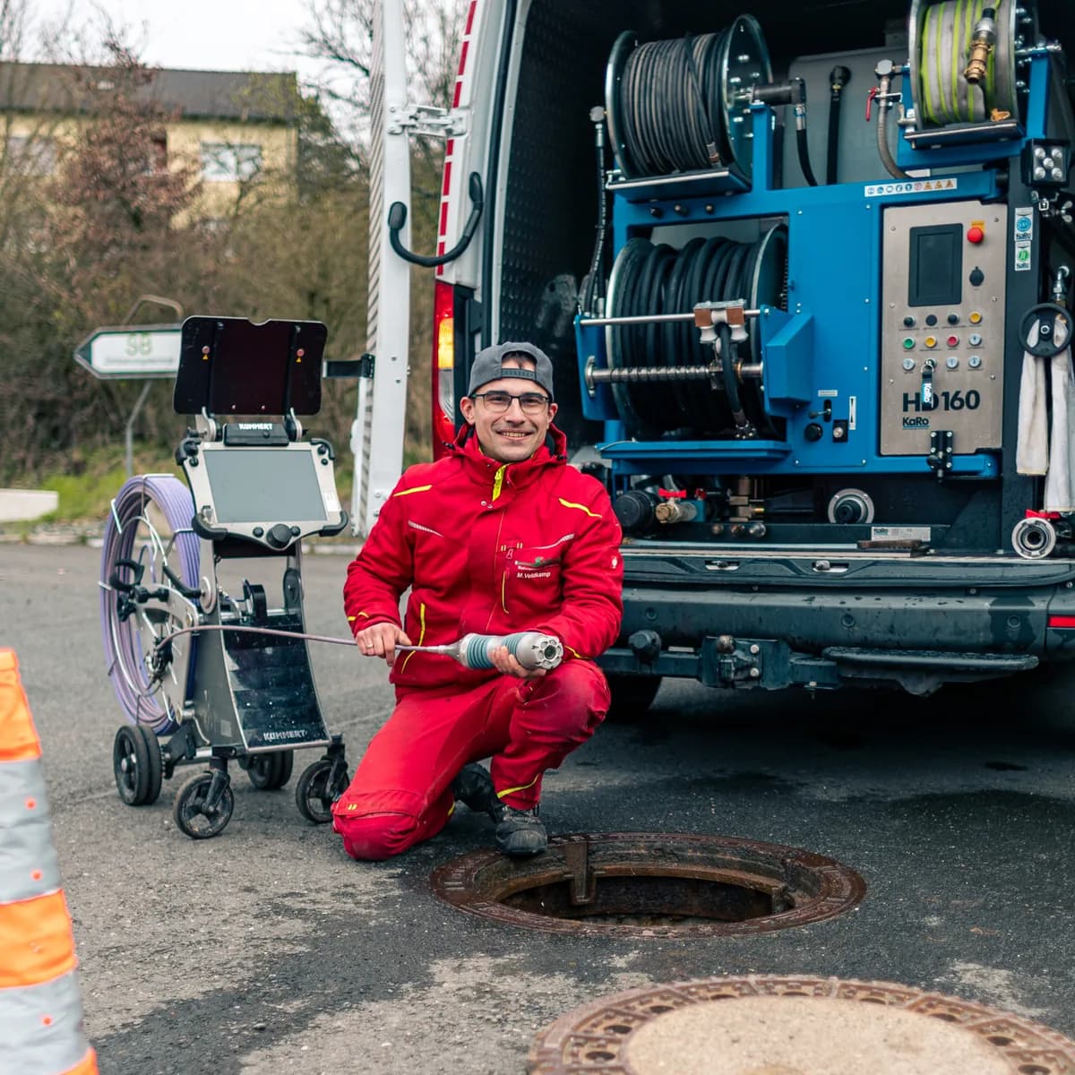 Techniker der Hermann Schäfer Rohrreinigungsservice e.K. am geöffneten Kanalschacht vor dem Einsatzfahrzeug mit Hochdruck-Spültechnik